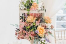17 a bird cage on a stand filled with various blooms and leaves