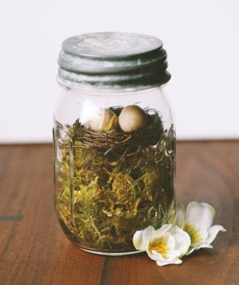 a mason jar with moss and a faux bird nest is a cool Easter terrarium