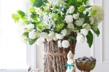 19 a white hydrangea centerpiece with a vase decorated with sticks and twine on a wooden slice