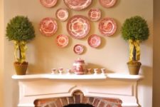 19 matching red and white plates in different sizes over the fireplace