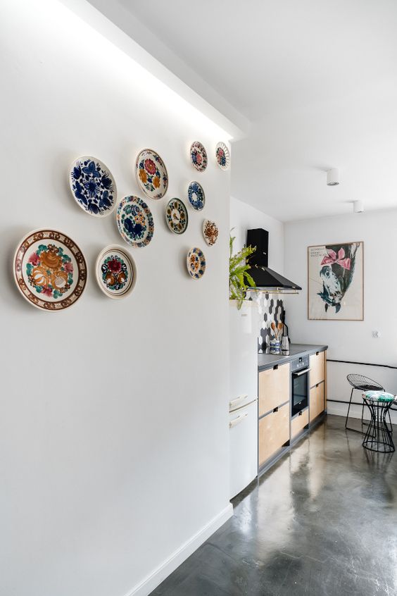 a colorful plate wall is a creative and bold addition to quite a neutral modern kitchen, it brings interest to the space