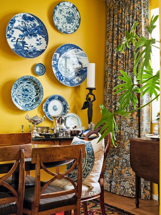 a mellow yellow wall with a bold chinoiserie plate wall looks adorable, chic and bright and brings interest to the room