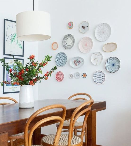 a stained table and vintage chairs paired with a pastel plate wall for decor are a cool combo, these plates add chic to the room