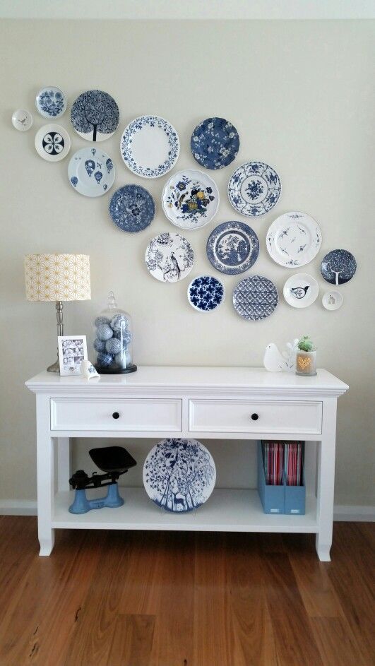 a white console table with a chinoiserie plate and blue baubles, a chinoiserie plate wall is a cool space