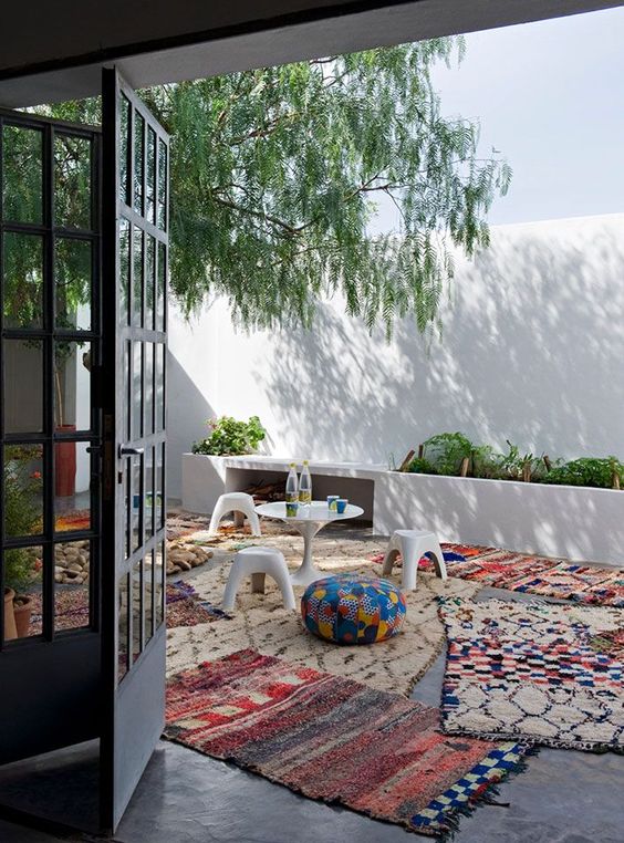 bold boho printed rugs covering the whole patio and colorful ottomans