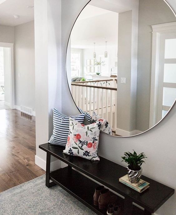 an oversized round mirror over the bench is a chic modern solution
