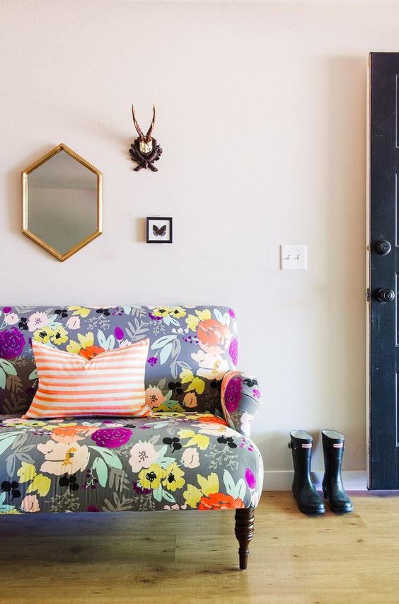 a small sofa with grey upholstery and bold floral prints