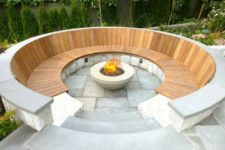 14 a modern stone and warm-colored wood round conversation pit with a fire