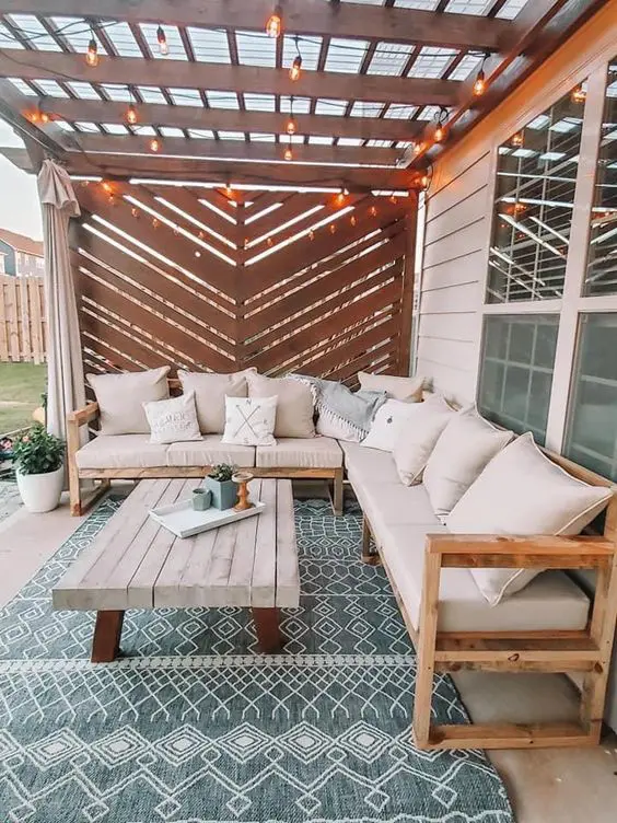 a boho terrace with a chevron screen, a white corner sofa, a coffee table, a boho rug and a potted plant