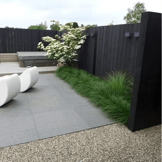 a modern dark toned vertical wooden fence creates a minimal feel in the space, and concrete tile and modern furniture look perfect in this backdrop