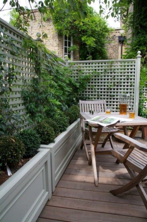 a small deck with folding furniture, planters with privacy screens, with greenery and vines climbing up