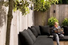 04 a wooden corner sofa with black cushions and pillows