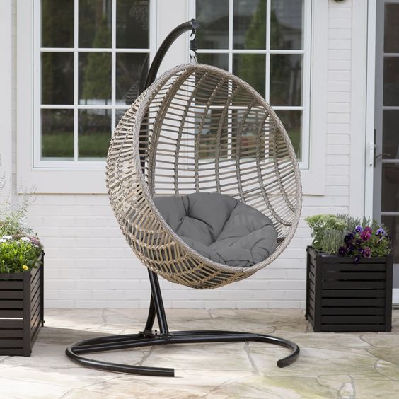 a hanging egg chair with a cushion and a metal stand will make your outdoor space modern