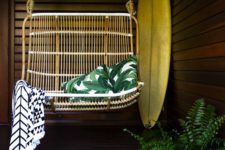 02 a 70s inspired rattan swing with a couple of pillows and a geo blanket looks very chic