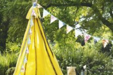 02 a colorful yellow teepee with printed blankets and pillows and fabric garlands