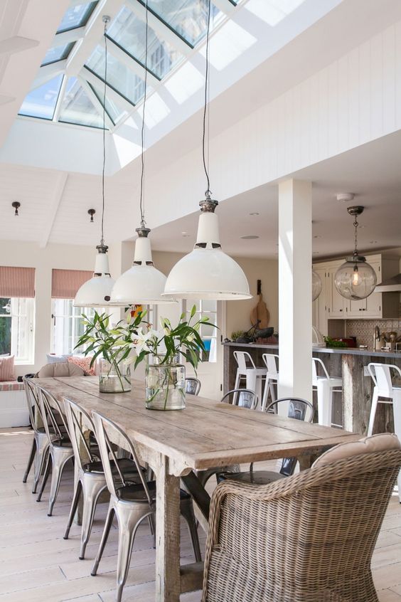 a cozy dining space with a rustic wooden table, a rattan chair and metal chairs with skylights above
