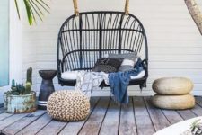 03 a beachside deck with a black rattan swing and some black and white pillows looks trendy