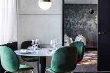 07 emerald velvet chairs with copper legs stand out in a minimalist dining space with concrete walls
