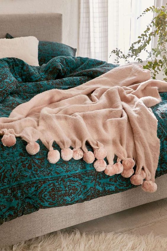 a blush blanket with pompoms is a cozy and cute idea for summer