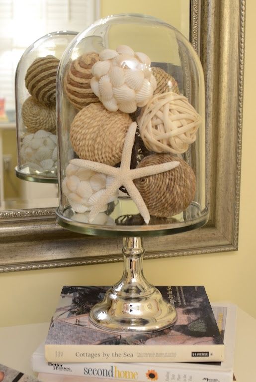 a cloche with a star fish, shell covered balls and jute balls