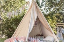 09 a neutral fabric teepee for kids, with printed pillows and blankets and a pompom trim