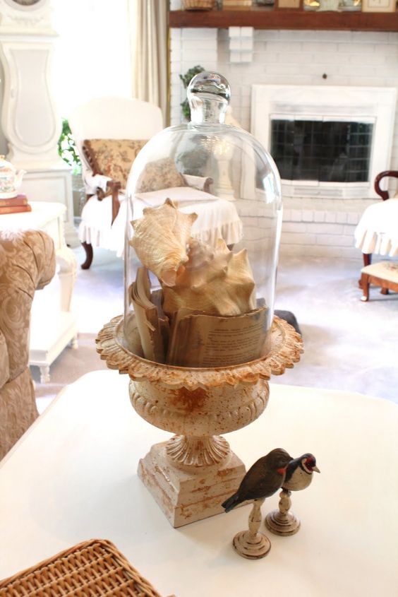 a vintage cloche display with book pages and shells