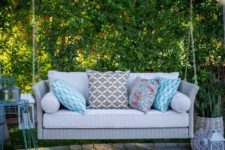 12 a light grey wicker swing with printed pillows will fit any modern backyard