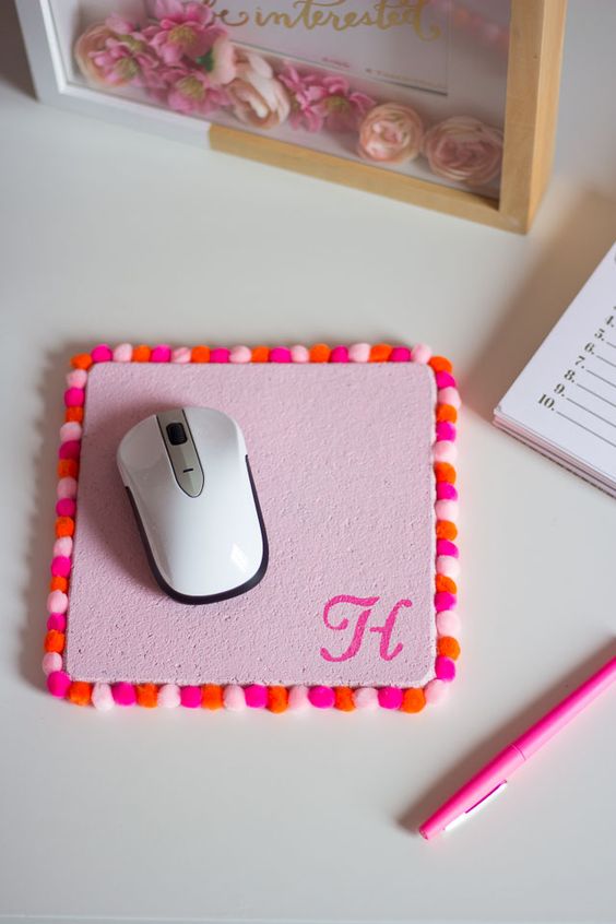 a pink mouse pad is made more summer like with colorful pompoms