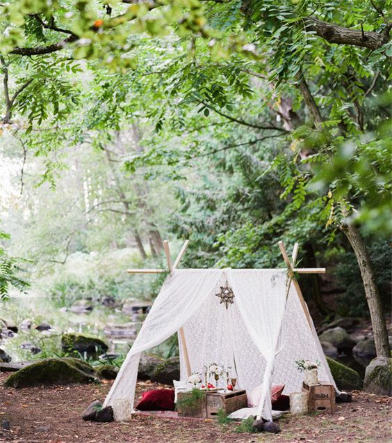 a small teepee with white lace fabric, a candle lantern and crate coffee table