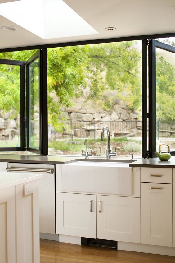 a black framed folding window as the kitchen's backsplash allows breathing fresh air