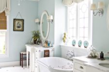 a coastal bathroom in light blue with a small glam chandelier to spruce it up