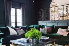 06 a dark space with a large emerald sectional sofa and brass touches