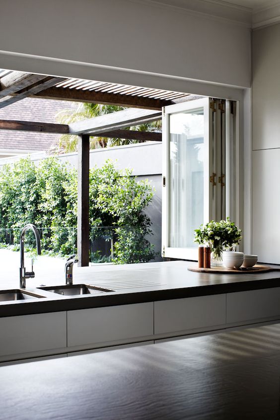 a folding window opens the kitchen to outdoors, and turns it into an outdoor indoor space