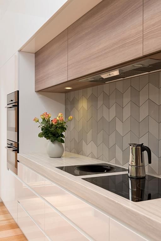 herringbone clad tiles in grey shades make the wooden kitchen look modern