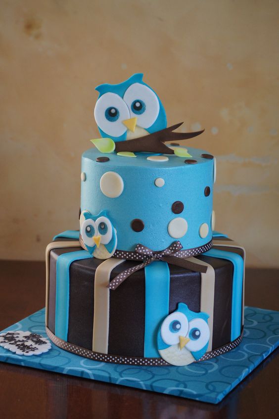 a blue and brown owl cake for a boy's baby shower with bows and ribbons