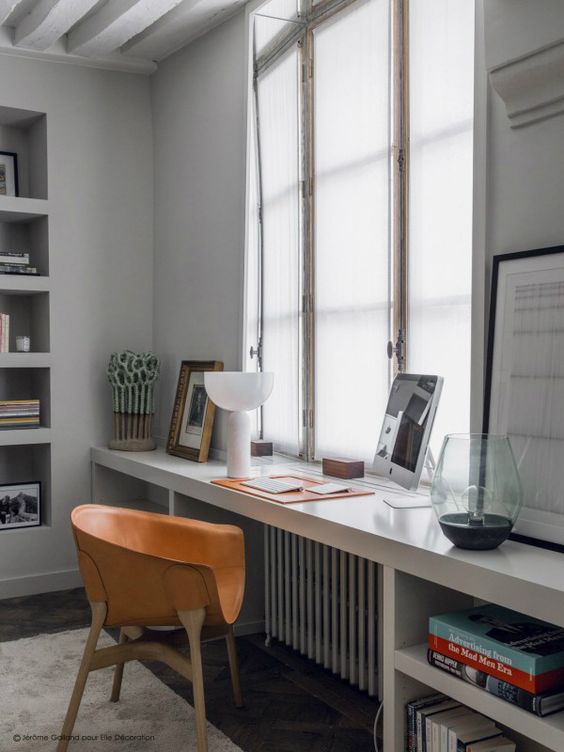 a thick sleek windowsill used as a workspace and some built-in shelves