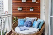 12 a wood wall and deck with planters, a wicker chair with pillows and a cushion