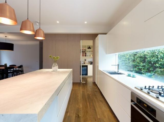 matte white kitchen with a window backsplash that shows much greenery