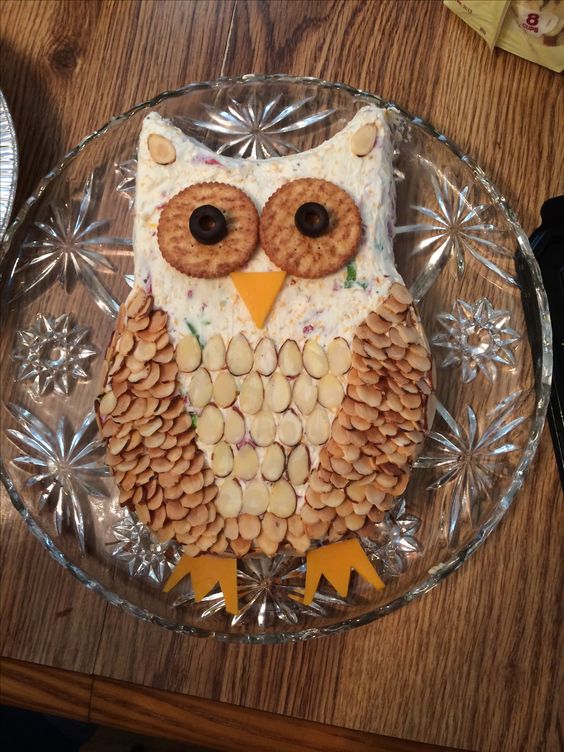 an owl cheese ball with crackers for eyes and slivered almonds for feathers