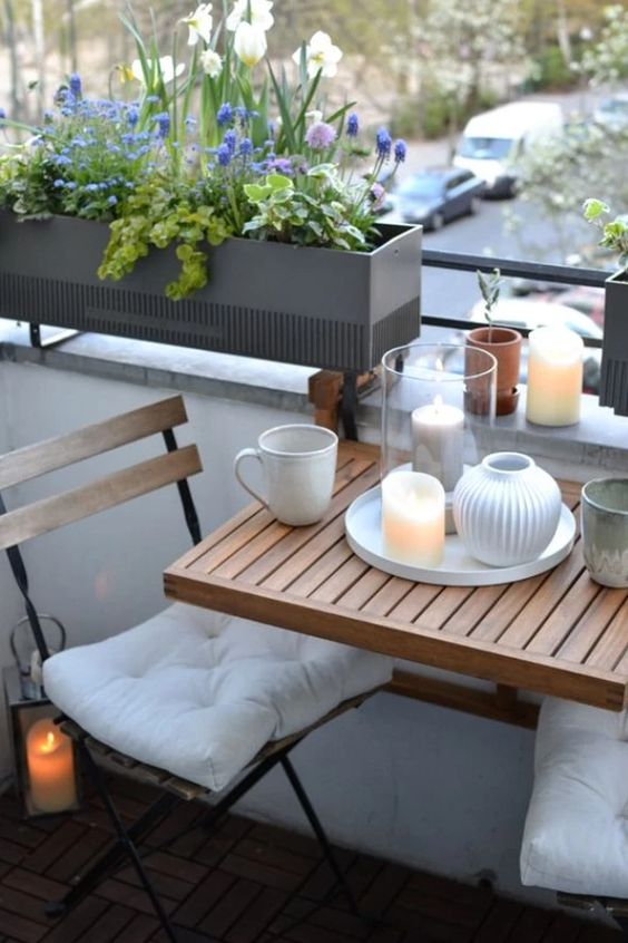 a Scandinavian balcony with folding furniture, a railing balcony and some candles and lanterns