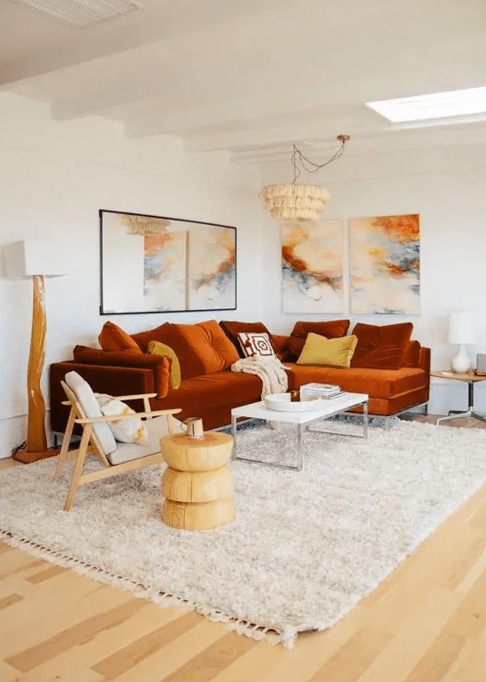 A bold living room with a rust colored modern sectional and a bright gallery wall plus statement lamps