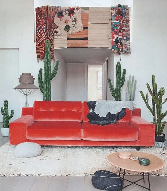 a desert-inspired space with a fiery-red velvet sofa and cacti, real and faux ones, with bold boho textiles