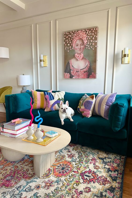 a dopamine infused living room with paneling, a dark green velvet sofa with pillows, a coffee table, a printed rug, colorful candles and a bold artwork