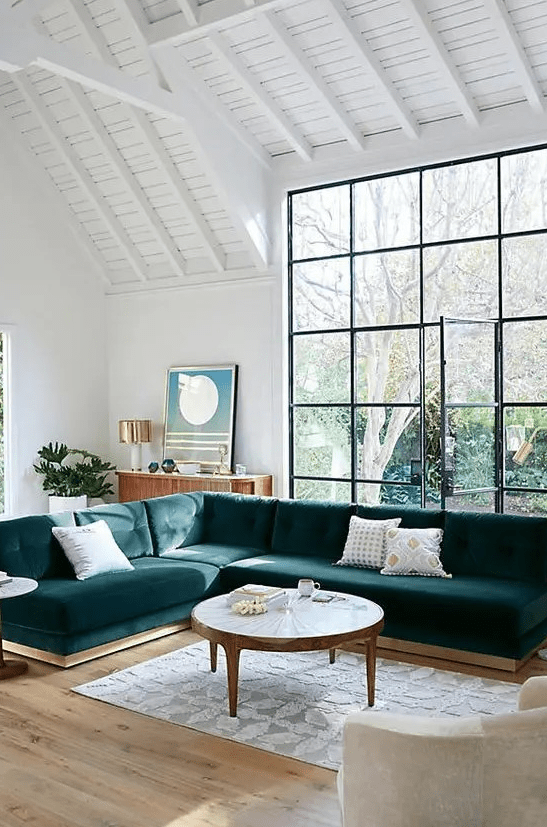 A large teal velvet L shaped sectional sofa is a statement piece in this airy space