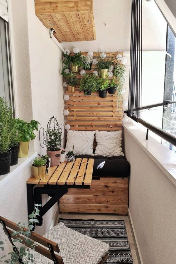 a little Scandi balcony with a planked shelf with pots and some planters on the windowsill plus some stained furniture