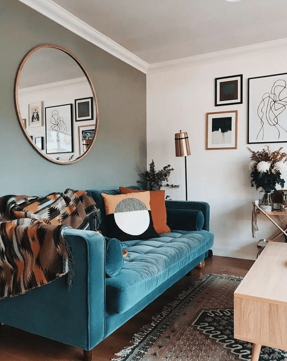 A stylish mid century modern living room with a grey accent wall, a turquoise sofa, printed textiles and a monochromatic gallery wall
