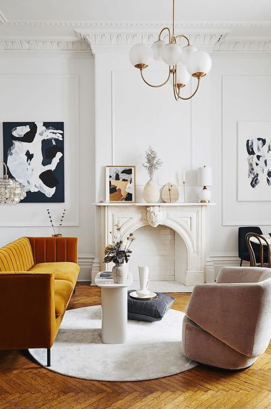 An exquisite Parisian living room with a non working fireplace, a honey yellow sofa, a blush chair, a retro chandelier and lovely art