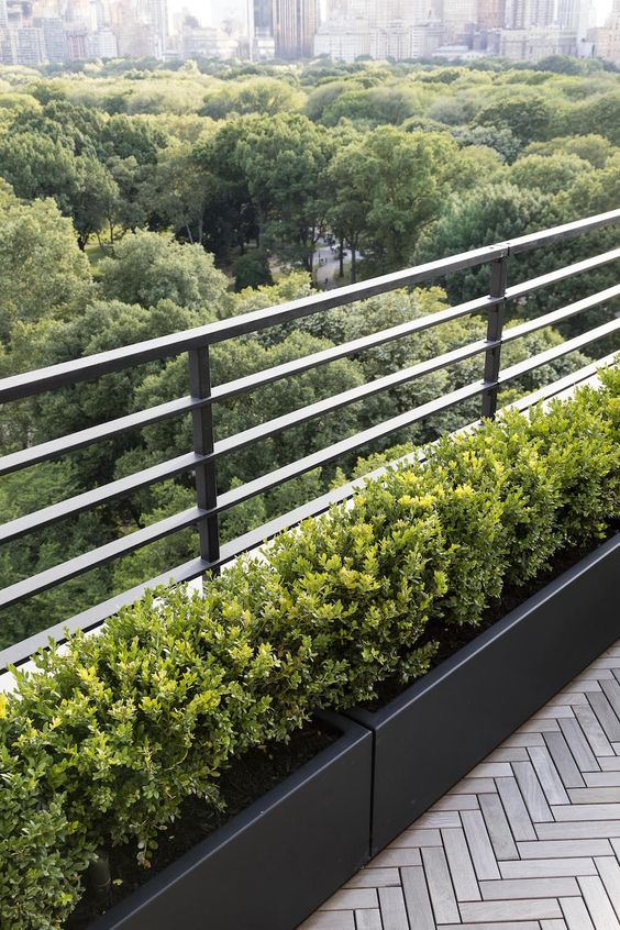 elegant long black planters with greenery are a cool and very modern solution for a balcony, whether it’s small or not