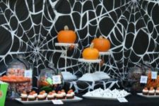 02 a black and orange dessert table with paper fans, spider webs, banners and orange pumpkins