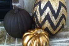a chic pumpkin trio of a matte black, glossy gold and a chevron black and gold glitter pumpkin